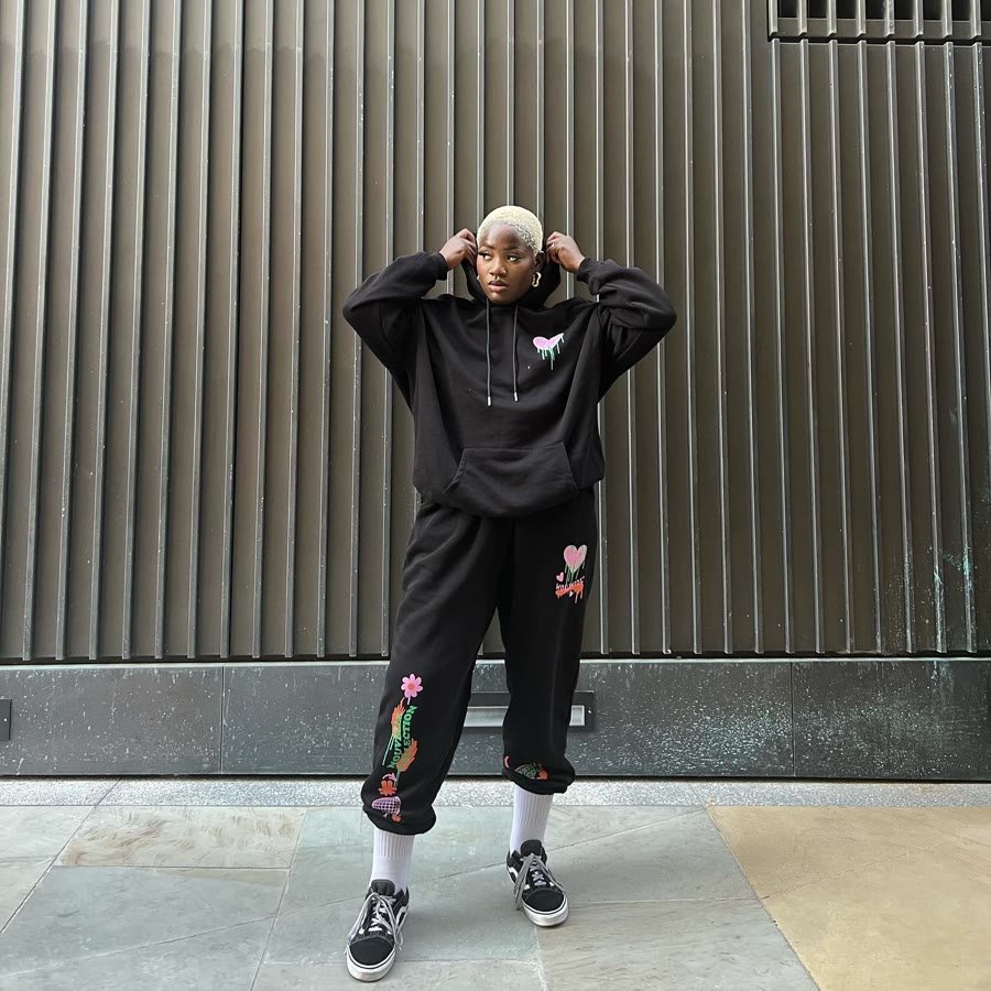 Black embroidered tracksuit against a corrugated wall